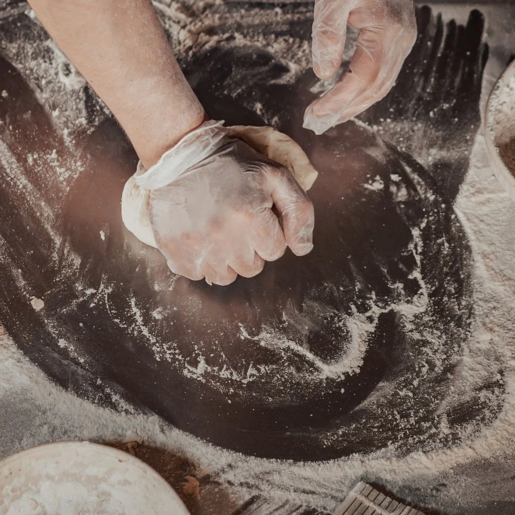 A home baker in Texas pulls a sourdough boule from a Dutch oven in a sunlit kitchen.